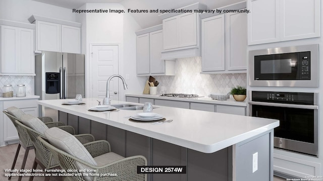 kitchen featuring white cabinets, appliances with stainless steel finishes, sink, a breakfast bar, and a center island with sink