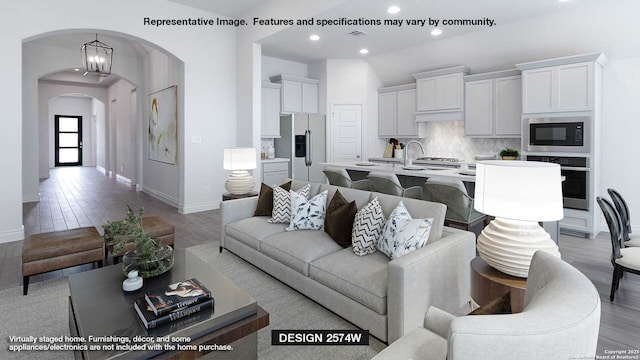 living room with a notable chandelier, light hardwood / wood-style floors, and lofted ceiling