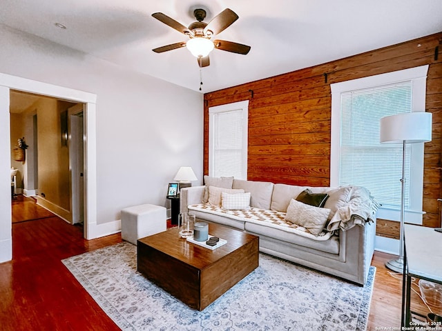 living room featuring ceiling fan and wood walls