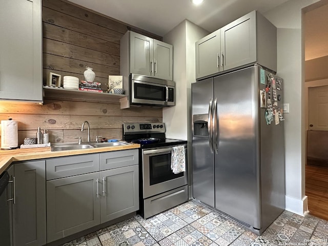 kitchen with sink, appliances with stainless steel finishes, and wooden walls