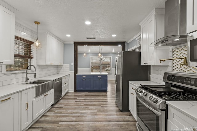 kitchen featuring white cabinetry, stainless steel appliances, and wall chimney exhaust hood