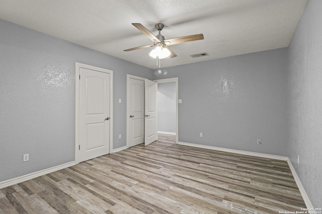 unfurnished bedroom featuring ceiling fan, light hardwood / wood-style flooring, and a textured ceiling