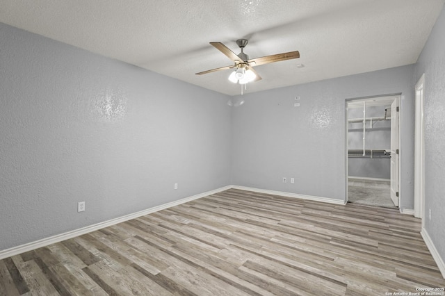 spare room with light hardwood / wood-style floors, a textured ceiling, and ceiling fan