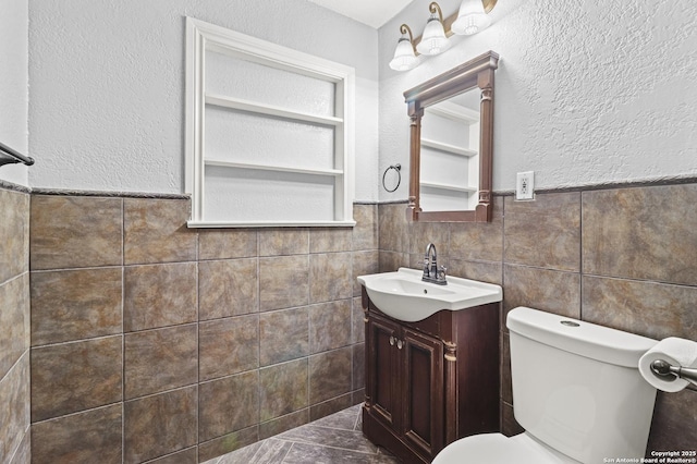 bathroom with built in features, toilet, tile walls, and vanity