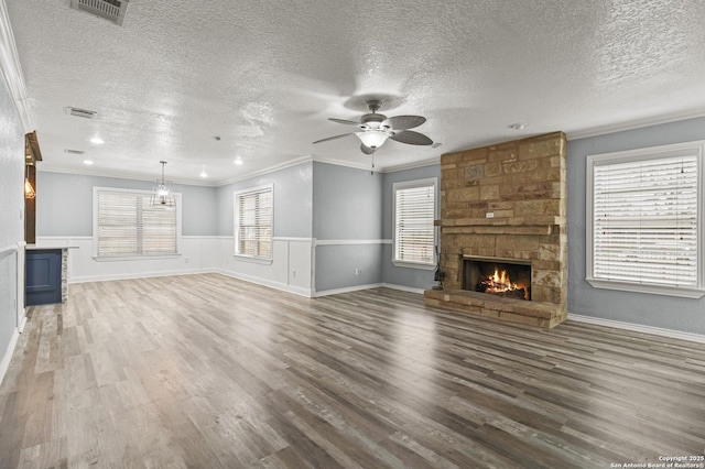 unfurnished living room with crown molding, ceiling fan, dark hardwood / wood-style flooring, a fireplace, and a textured ceiling