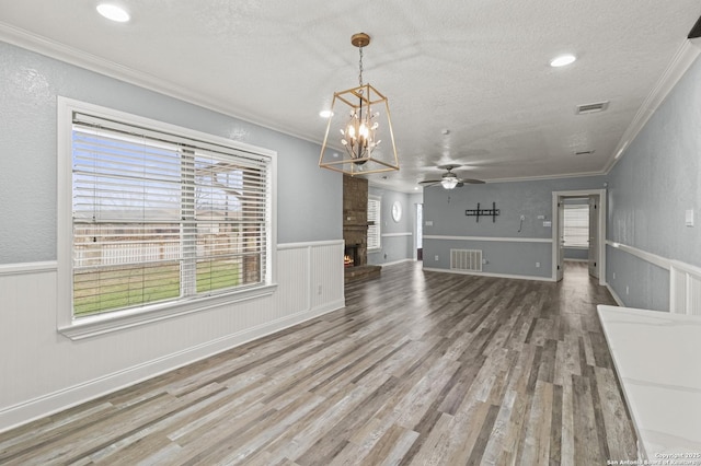 unfurnished dining area featuring ornamental molding, a textured ceiling, a fireplace, and wood-type flooring