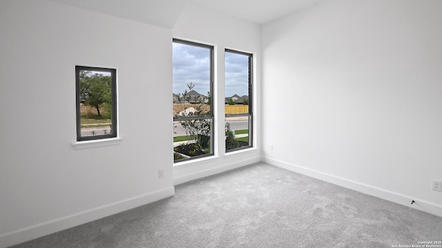 carpeted empty room featuring baseboards