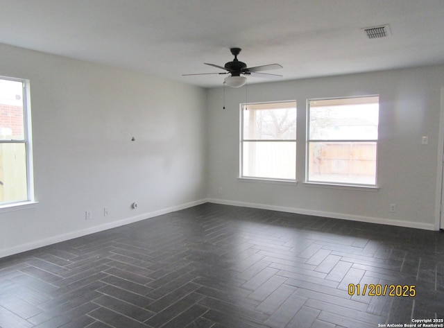 empty room with ceiling fan and a wealth of natural light