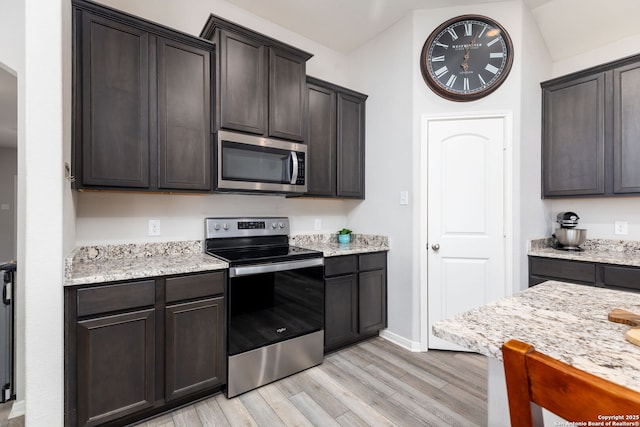 kitchen with dark brown cabinetry, appliances with stainless steel finishes, and light hardwood / wood-style flooring