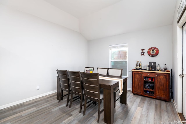 dining area featuring hardwood / wood-style floors and vaulted ceiling