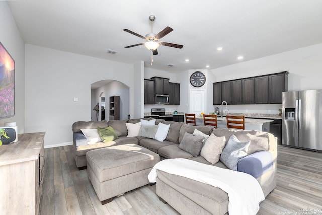 living room with ceiling fan, sink, and light wood-type flooring