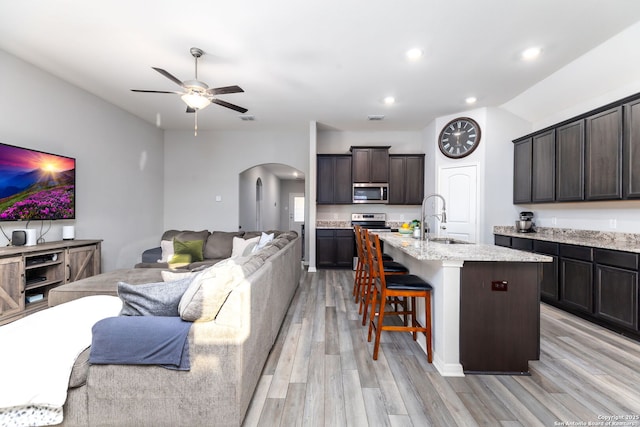 kitchen featuring sink, dark brown cabinets, light hardwood / wood-style flooring, and an island with sink