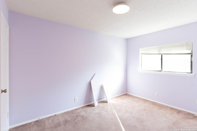 empty room with light colored carpet and a textured ceiling