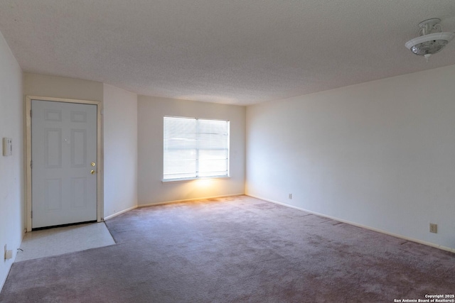 carpeted empty room featuring a textured ceiling