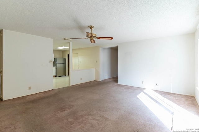 unfurnished room featuring a textured ceiling, light colored carpet, and ceiling fan