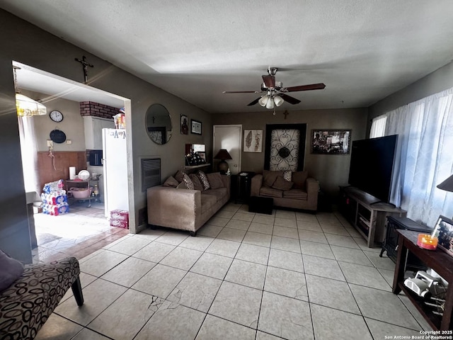 tiled living room with a textured ceiling and ceiling fan