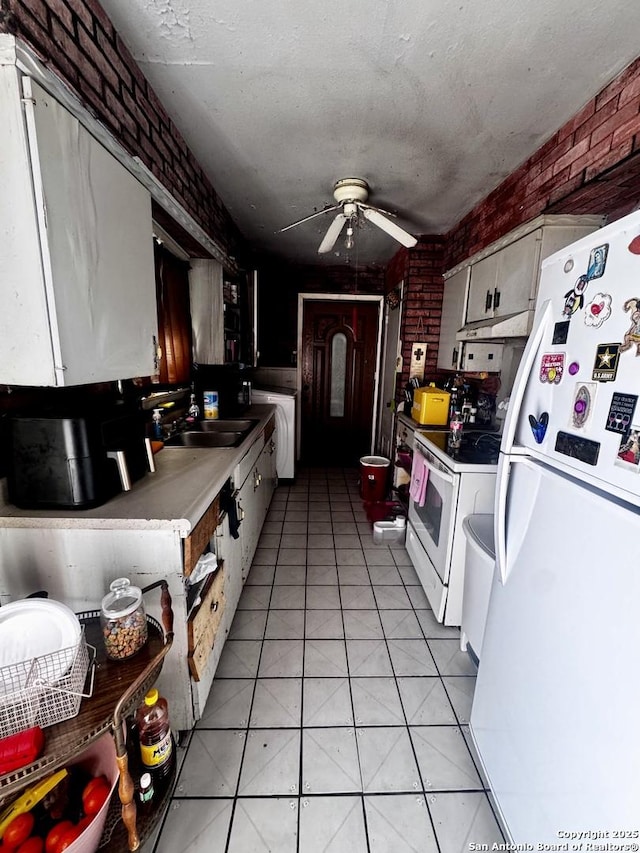 kitchen with ceiling fan, sink, white appliances, a textured ceiling, and brick wall