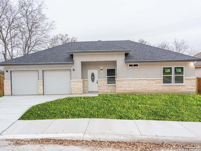 prairie-style house featuring a garage and a front lawn