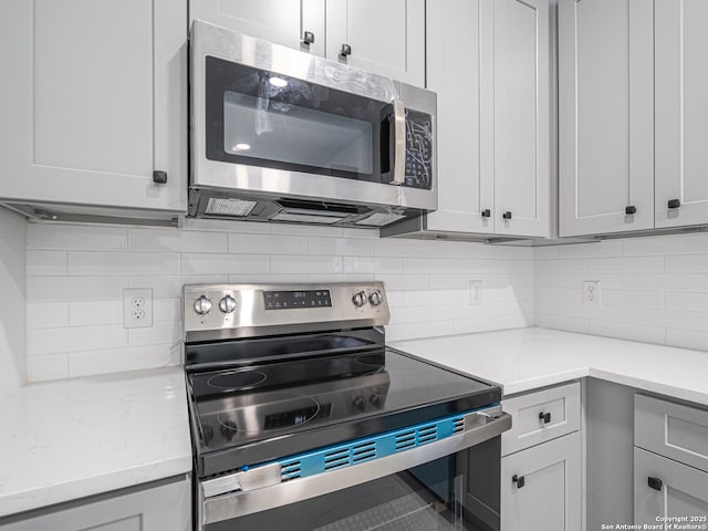 kitchen with decorative backsplash, light stone countertops, and appliances with stainless steel finishes