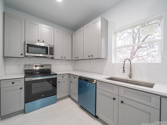 kitchen with sink, gray cabinets, stainless steel appliances, and tasteful backsplash