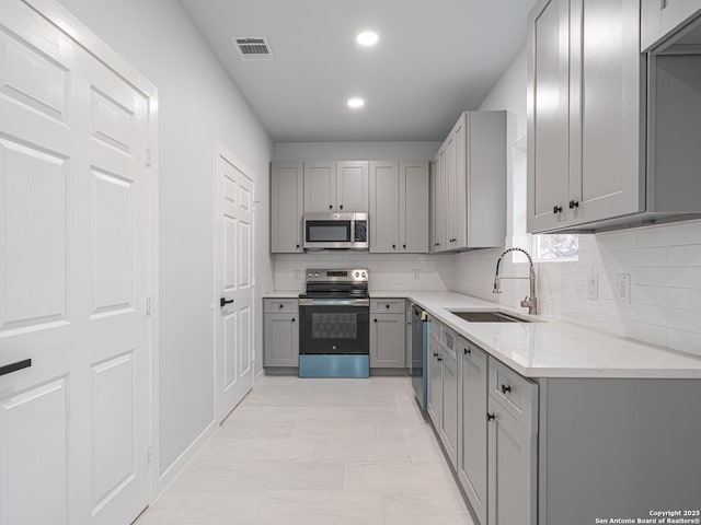 kitchen with sink, gray cabinetry, stainless steel appliances, and tasteful backsplash