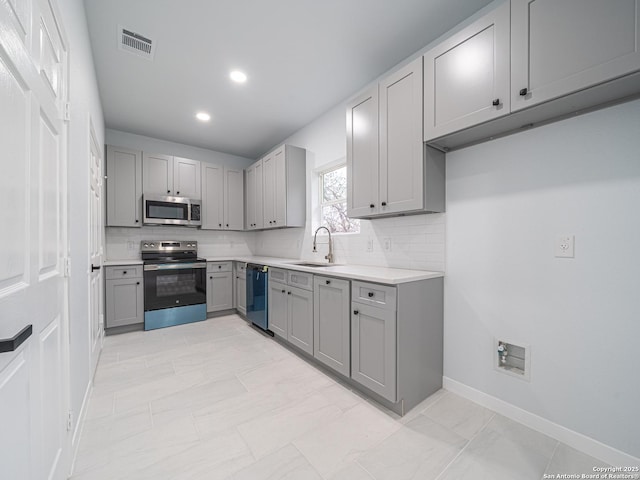 kitchen with sink, backsplash, gray cabinets, and stainless steel appliances