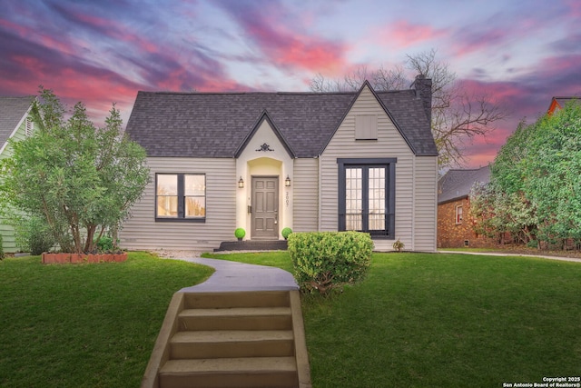 view of front of home featuring roof with shingles and a lawn