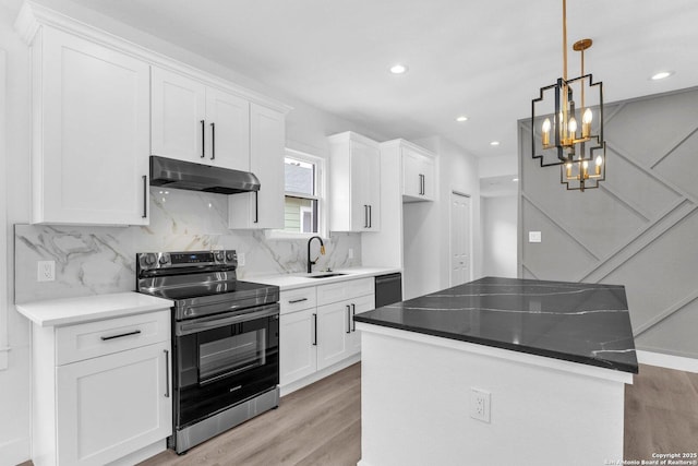 kitchen featuring stainless steel electric stove, decorative light fixtures, white cabinets, and a kitchen island