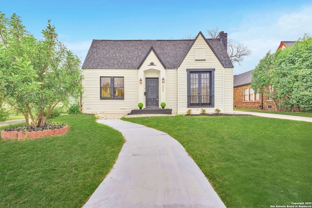 view of front of house featuring a shingled roof, a chimney, and a front lawn