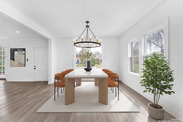 dining space featuring hardwood / wood-style flooring and an inviting chandelier