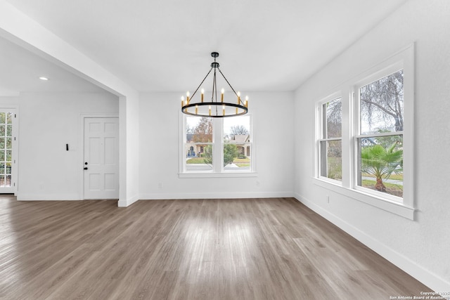 unfurnished dining area with hardwood / wood-style flooring and an inviting chandelier