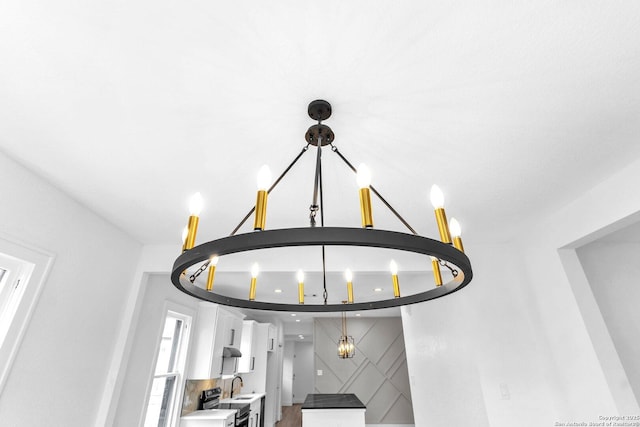 room details with white cabinets, a chandelier, electric range oven, and sink