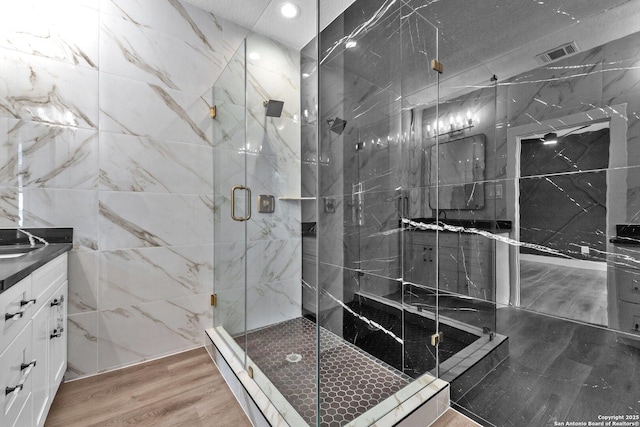 bathroom featuring hardwood / wood-style floors, walk in shower, and vanity