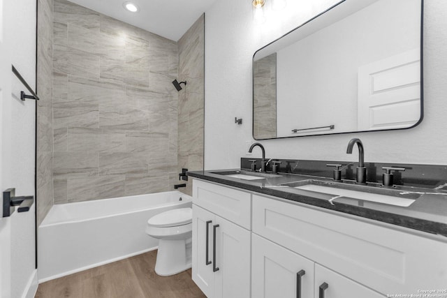 full bathroom with wood-type flooring, tiled shower / bath combo, vanity, and toilet