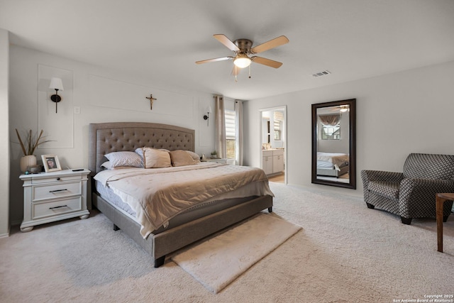 bedroom with light colored carpet, ensuite bath, and ceiling fan