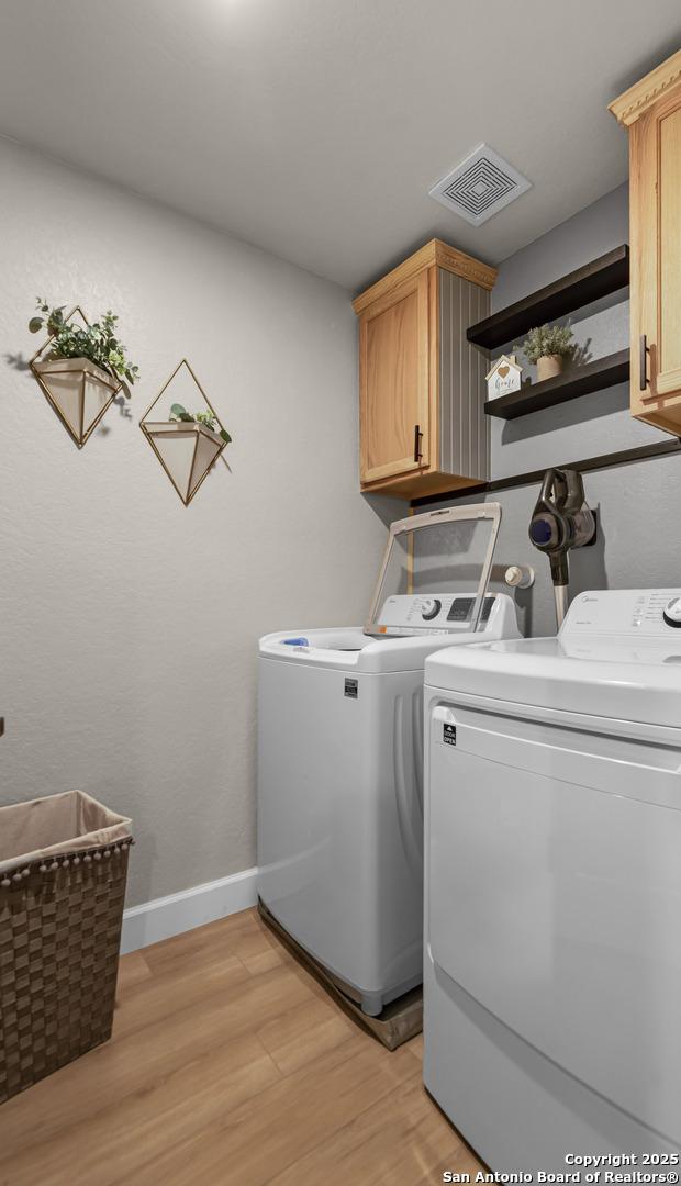 laundry area with cabinets, light hardwood / wood-style flooring, and separate washer and dryer