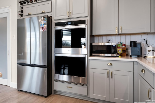 kitchen with decorative backsplash, light hardwood / wood-style floors, and appliances with stainless steel finishes