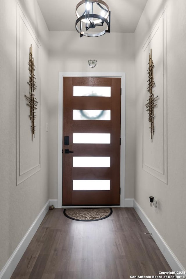 doorway to outside with a notable chandelier and dark wood-type flooring