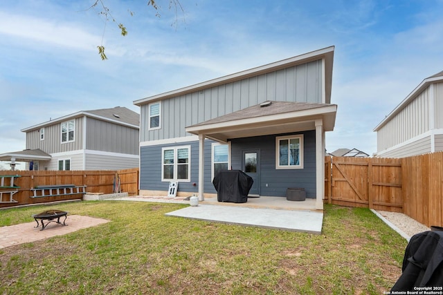 back of house featuring a patio area, a yard, and a fire pit