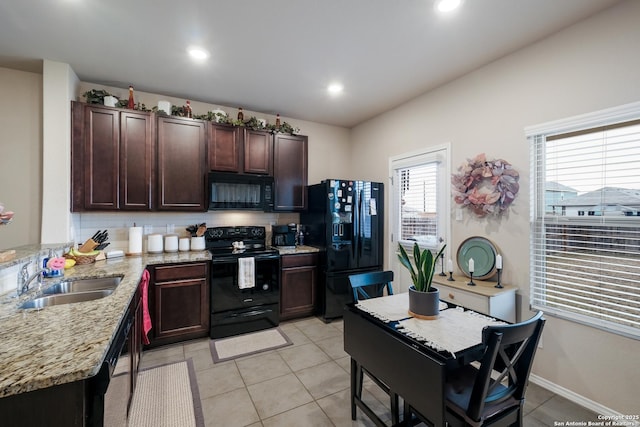 kitchen with sink, tasteful backsplash, light stone counters, light tile patterned flooring, and black appliances