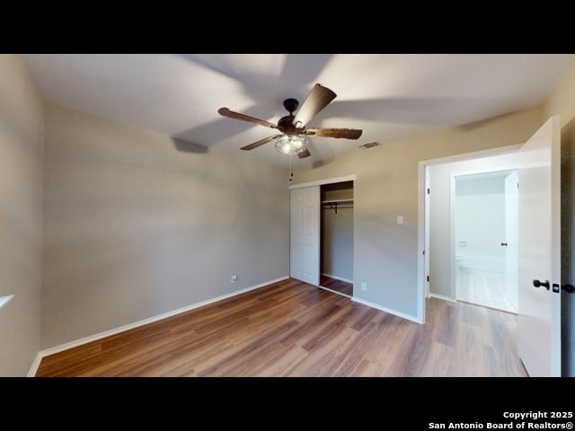 unfurnished bedroom featuring ceiling fan, hardwood / wood-style floors, and a closet