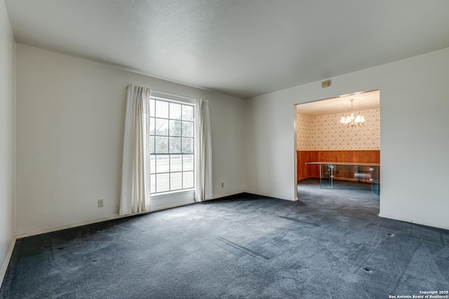 carpeted spare room with a chandelier