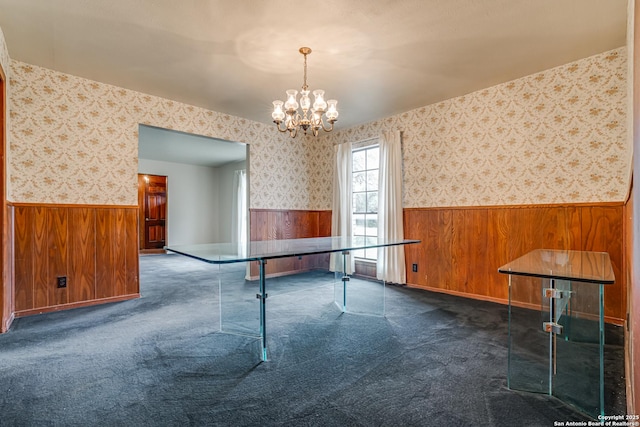 game room with wood walls, a chandelier, and dark carpet