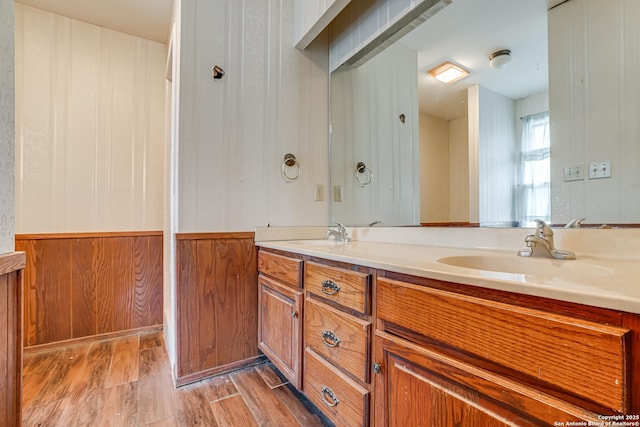 bathroom with hardwood / wood-style flooring, vanity, and wood walls