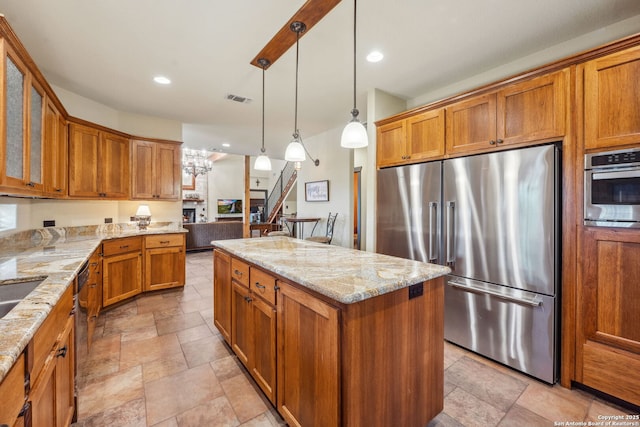 kitchen with stainless steel appliances, a center island, pendant lighting, and light stone counters