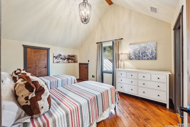 bedroom featuring lofted ceiling, hardwood / wood-style floors, and a notable chandelier