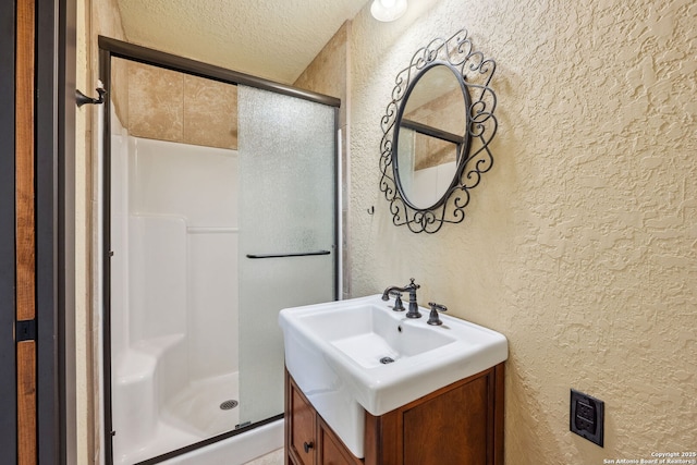 bathroom featuring walk in shower, vanity, and a textured ceiling