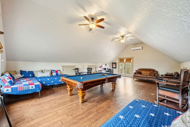 recreation room with billiards, vaulted ceiling, a textured ceiling, a wall unit AC, and hardwood / wood-style flooring