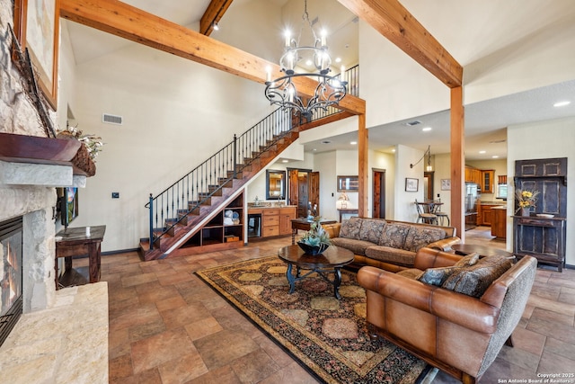 living room featuring an inviting chandelier, a premium fireplace, beam ceiling, and a high ceiling