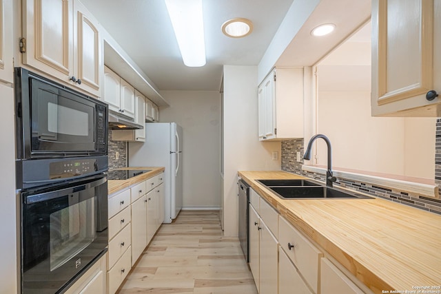 kitchen with sink, black appliances, decorative backsplash, and light wood-type flooring